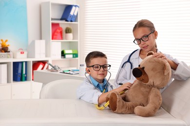 Photo of Little boy and girl with toy pretending to be doctors indoors