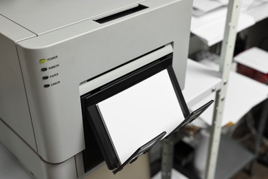 Photo of Modern printer with photo paper indoors, closeup. Printing house