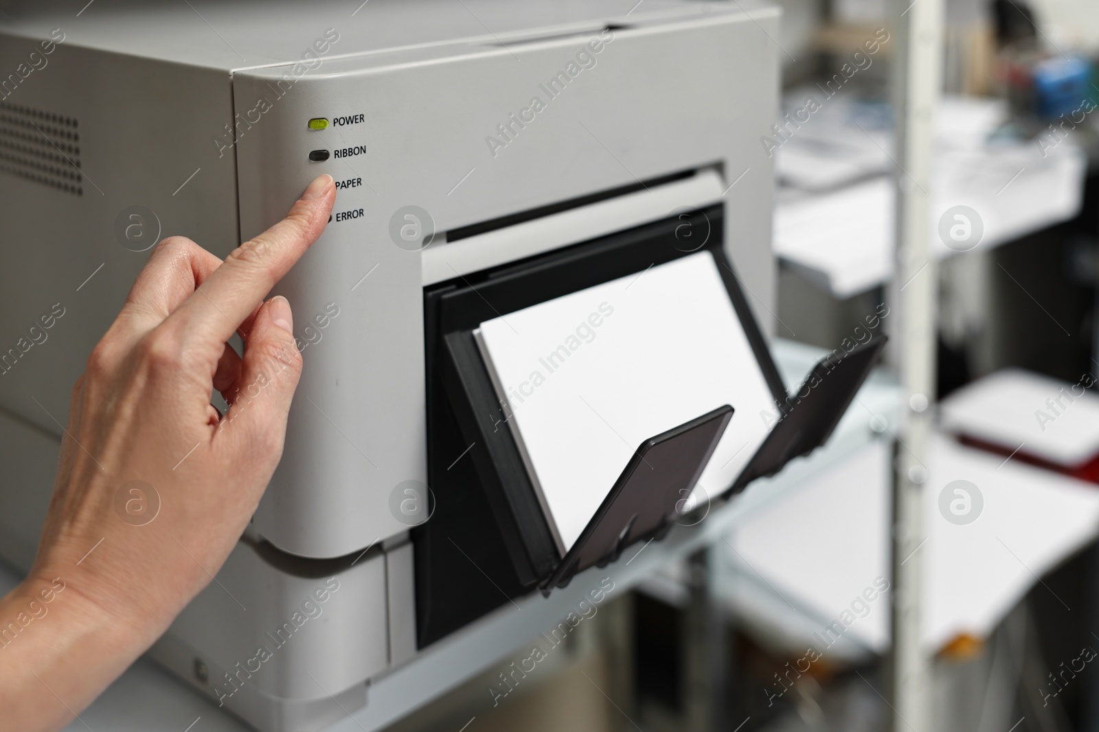 Photo of Woman using modern printer indoors, closeup. Printing house