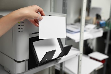 Photo of Woman with photo paper using modern printer indoors, closeup. Printing house