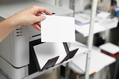 Photo of Woman with photo paper using modern printer indoors, closeup. Printing house