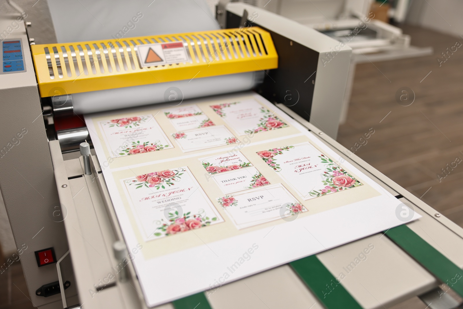 Photo of Modern roll laminator and paper sheet with invitation cards indoors, closeup. Printing house