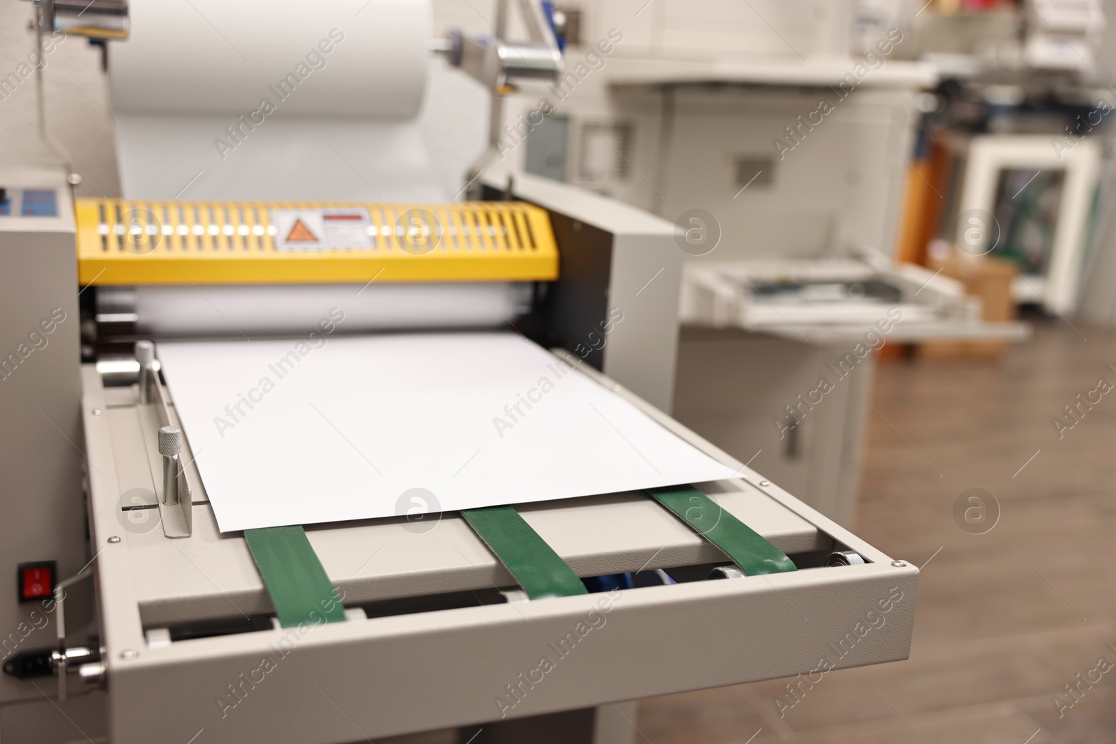 Photo of Modern roll laminator with paper indoors, closeup. Printing house