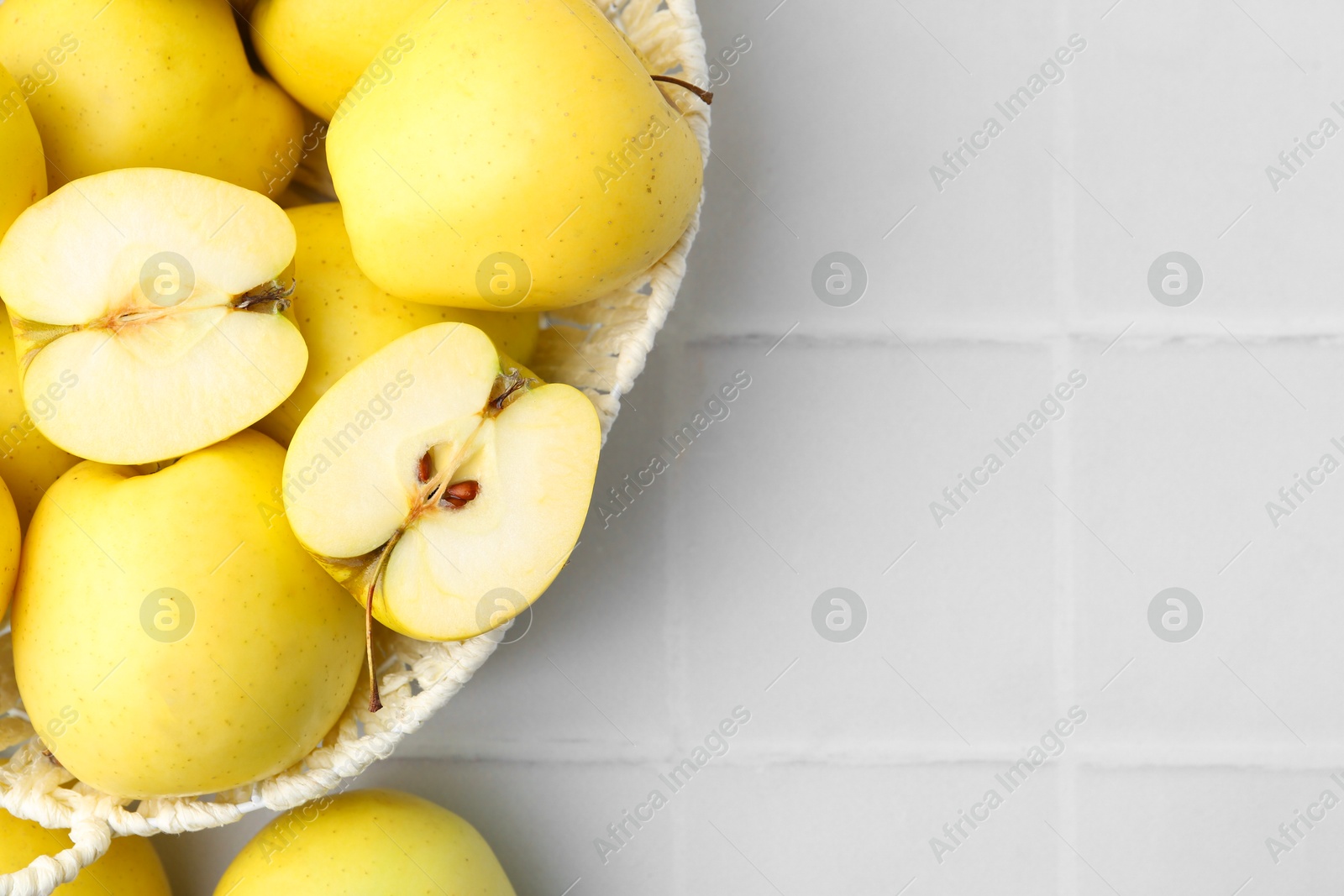 Photo of Fresh ripe yellow apples on white tiled table, flat lay. Space for text