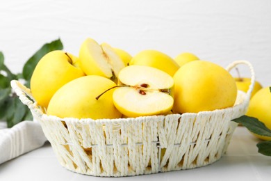 Photo of Fresh ripe yellow apples in basket on white tiled table, closeup