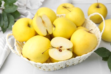 Photo of Fresh ripe yellow apples in basket on white tiled table, closeup