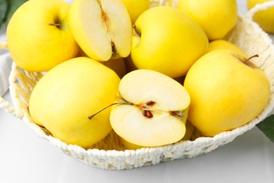 Photo of Fresh ripe yellow apples in basket on white table, closeup