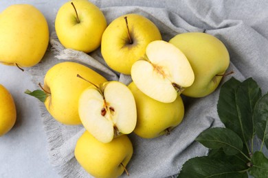 Photo of Fresh ripe yellow apples and green leaves on grey table, above view