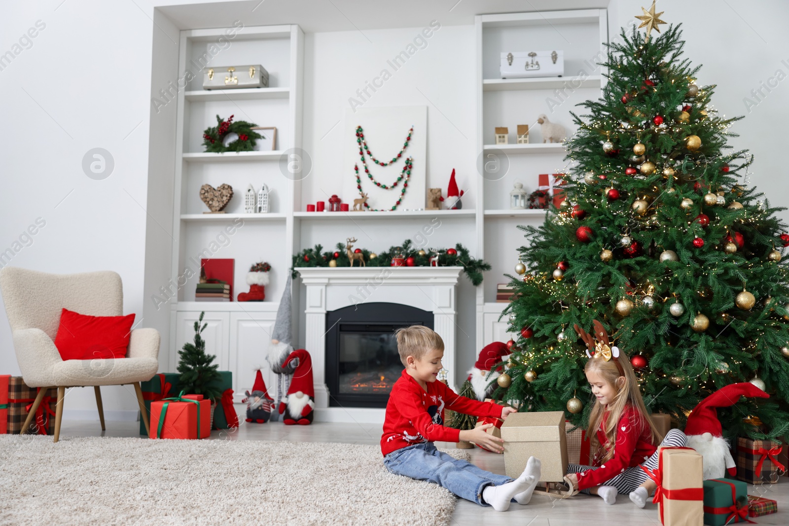 Photo of Little children with gifts near Christmas tree at home. Space for text