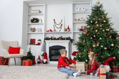 Little children with gifts near Christmas tree at home. Space for text