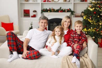 Happy family in pajamas on sofa at home. Christmas morning