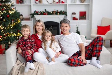 Photo of Happy family in pajamas on sofa at home. Christmas morning