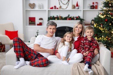 Happy family in pajamas on sofa at home. Christmas morning