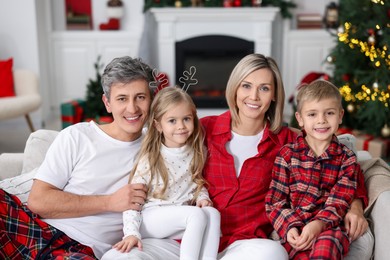 Photo of Happy family in pajamas on sofa at home. Christmas morning