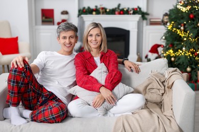 Photo of Lovely couple in pajamas on sofa at home. Christmas morning