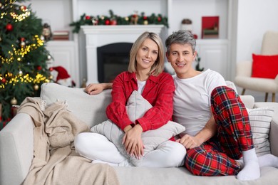 Photo of Lovely couple in pajamas on sofa at home. Christmas morning