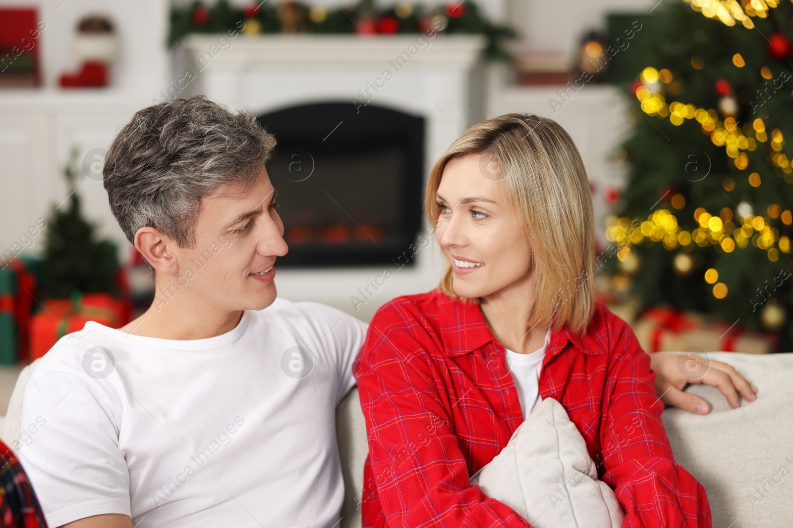 Photo of Lovely couple in pajamas on sofa at home. Christmas morning