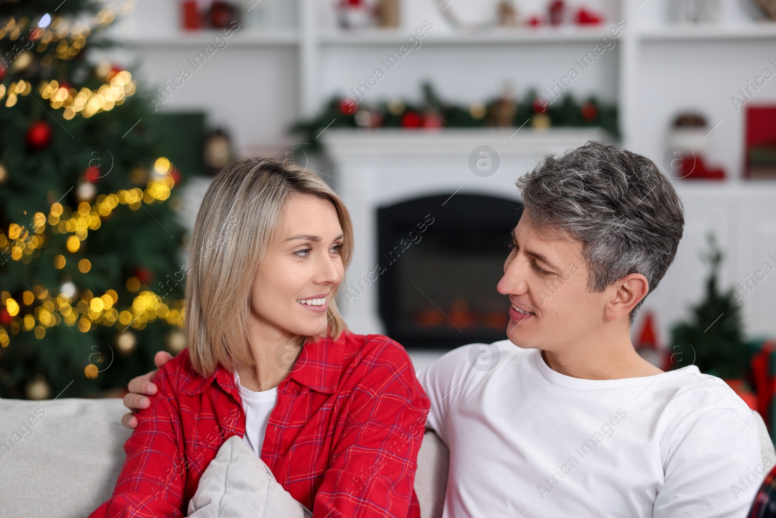 Photo of Lovely couple in pajamas on sofa at home. Christmas morning