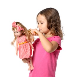 Cute little girl brushing doll's hair on white background