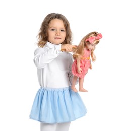 Photo of Cute little girl brushing doll's hair on white background