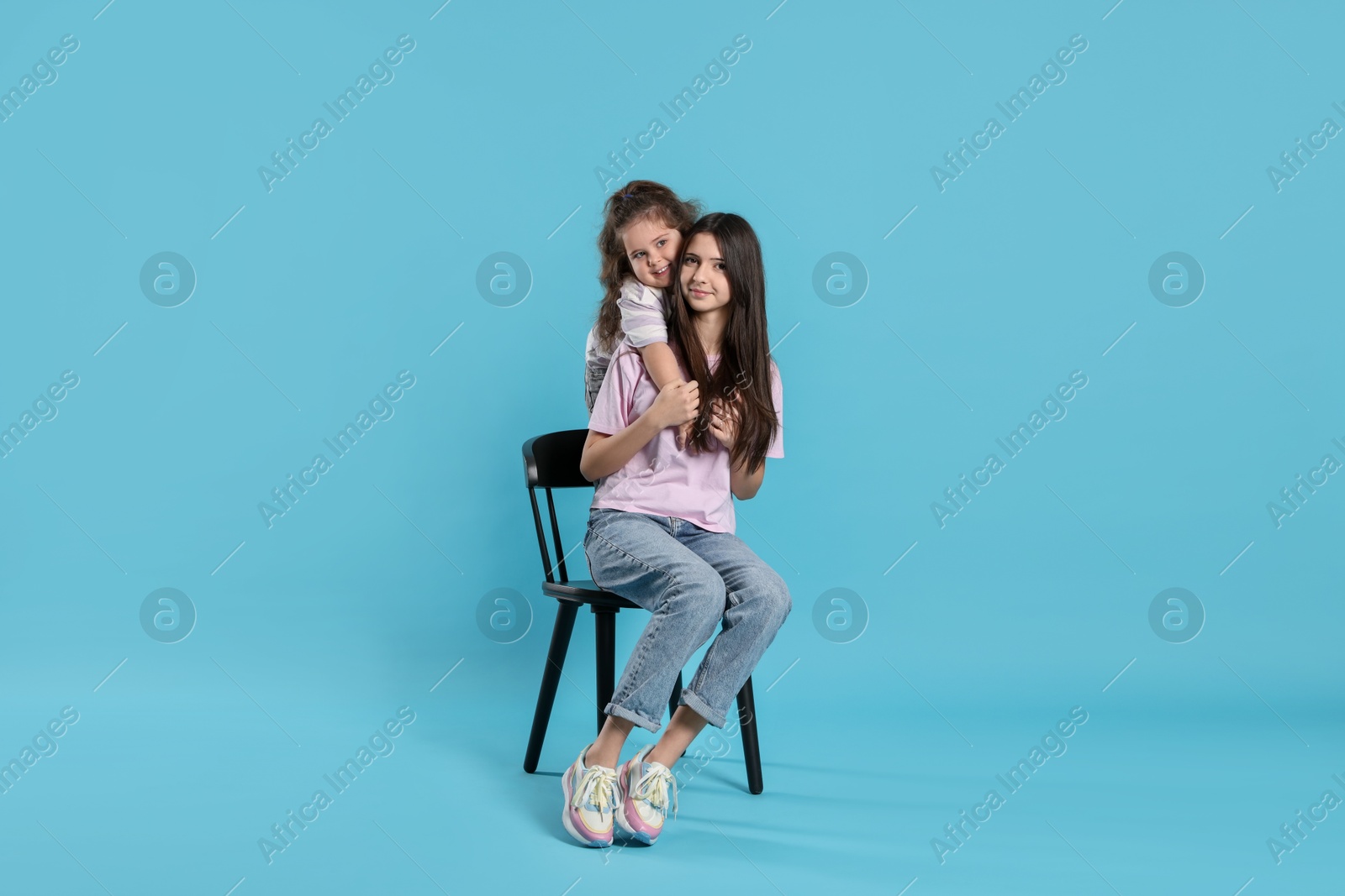 Photo of Portrait of cute sisters on light blue background