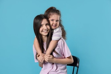 Photo of Portrait of cute sisters on light blue background