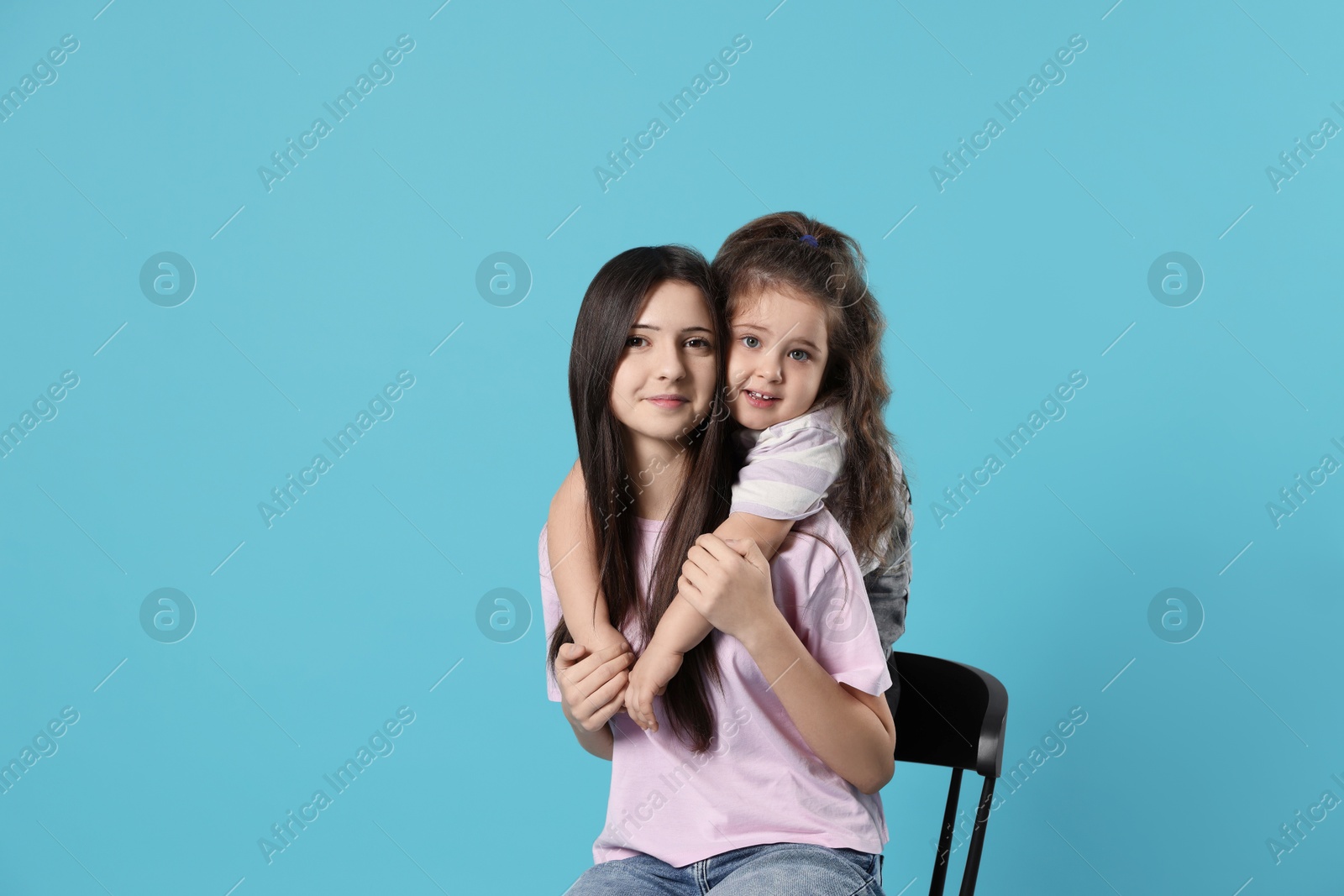 Photo of Portrait of cute sisters on light blue background