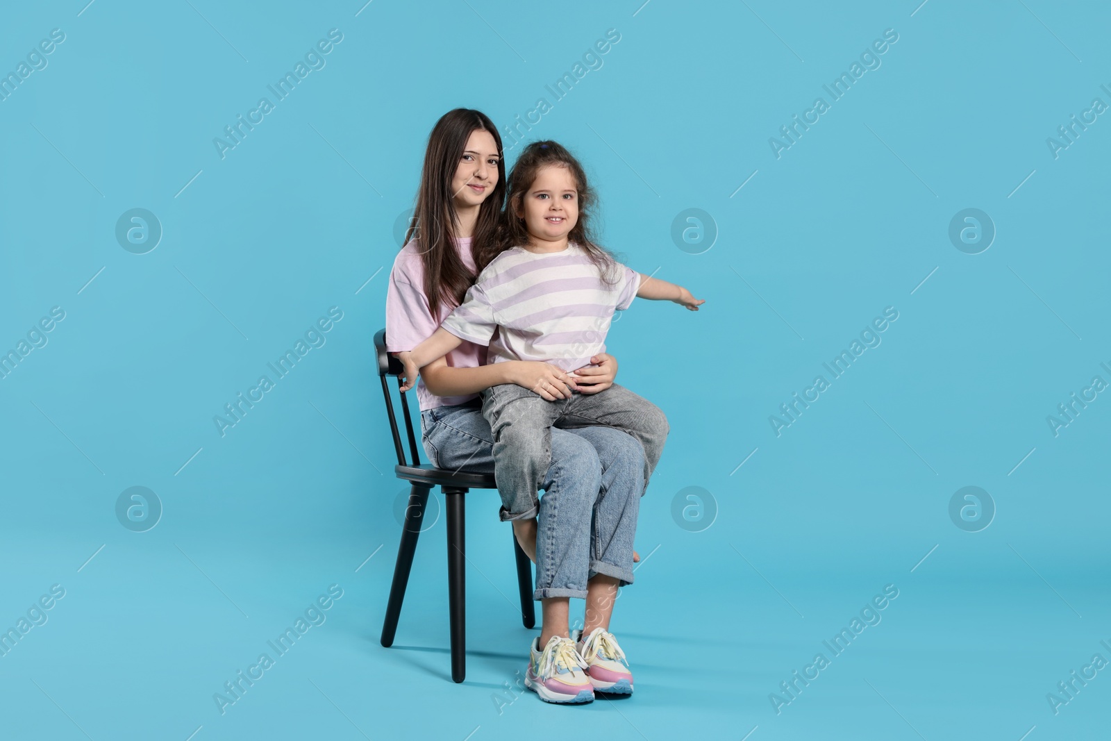 Photo of Portrait of cute sisters on light blue background