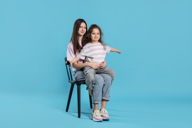 Photo of Portrait of cute sisters on light blue background