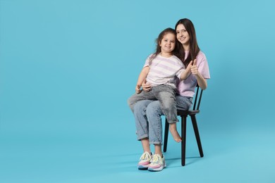 Photo of Portrait of cute sisters on light blue background