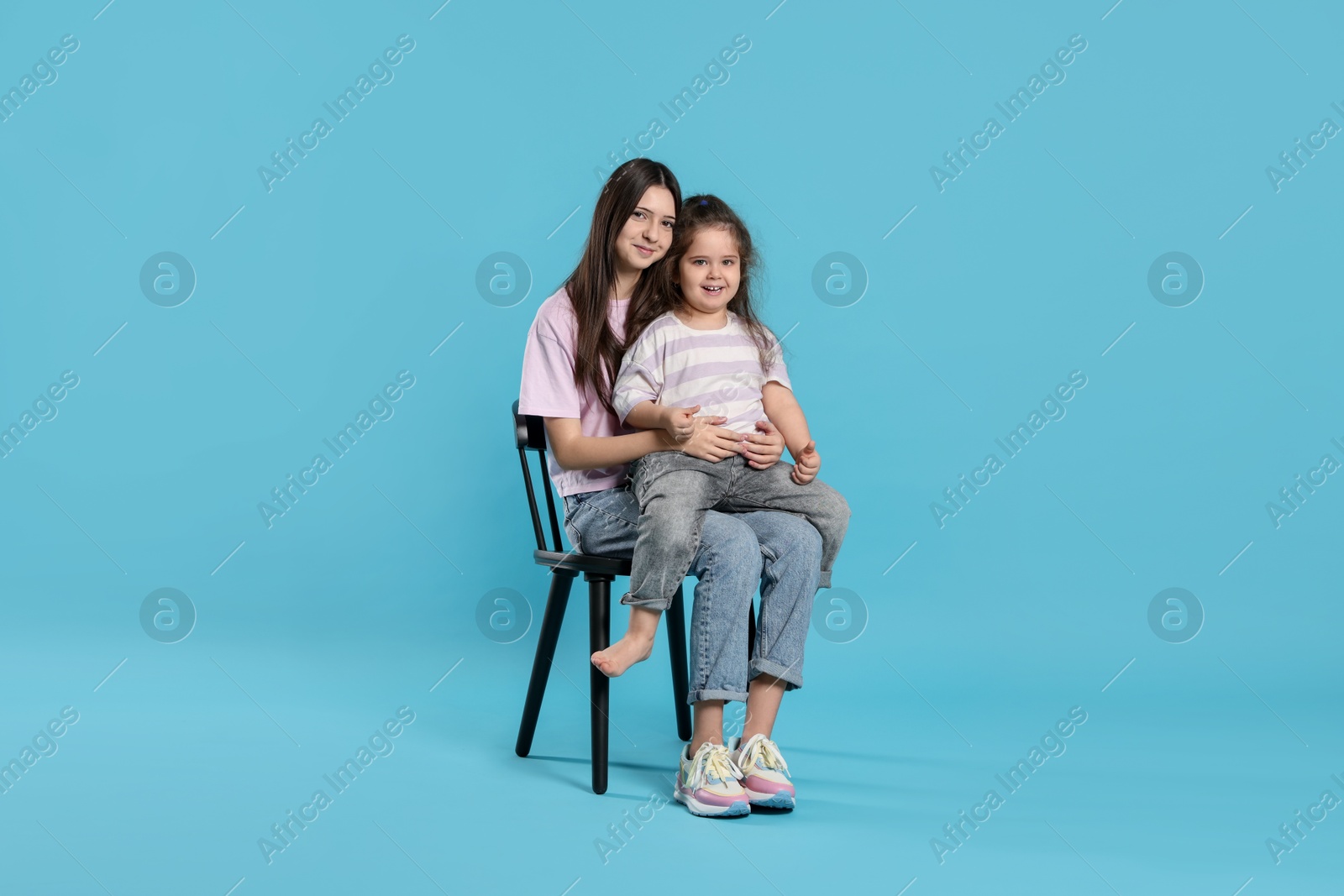 Photo of Portrait of cute sisters on light blue background