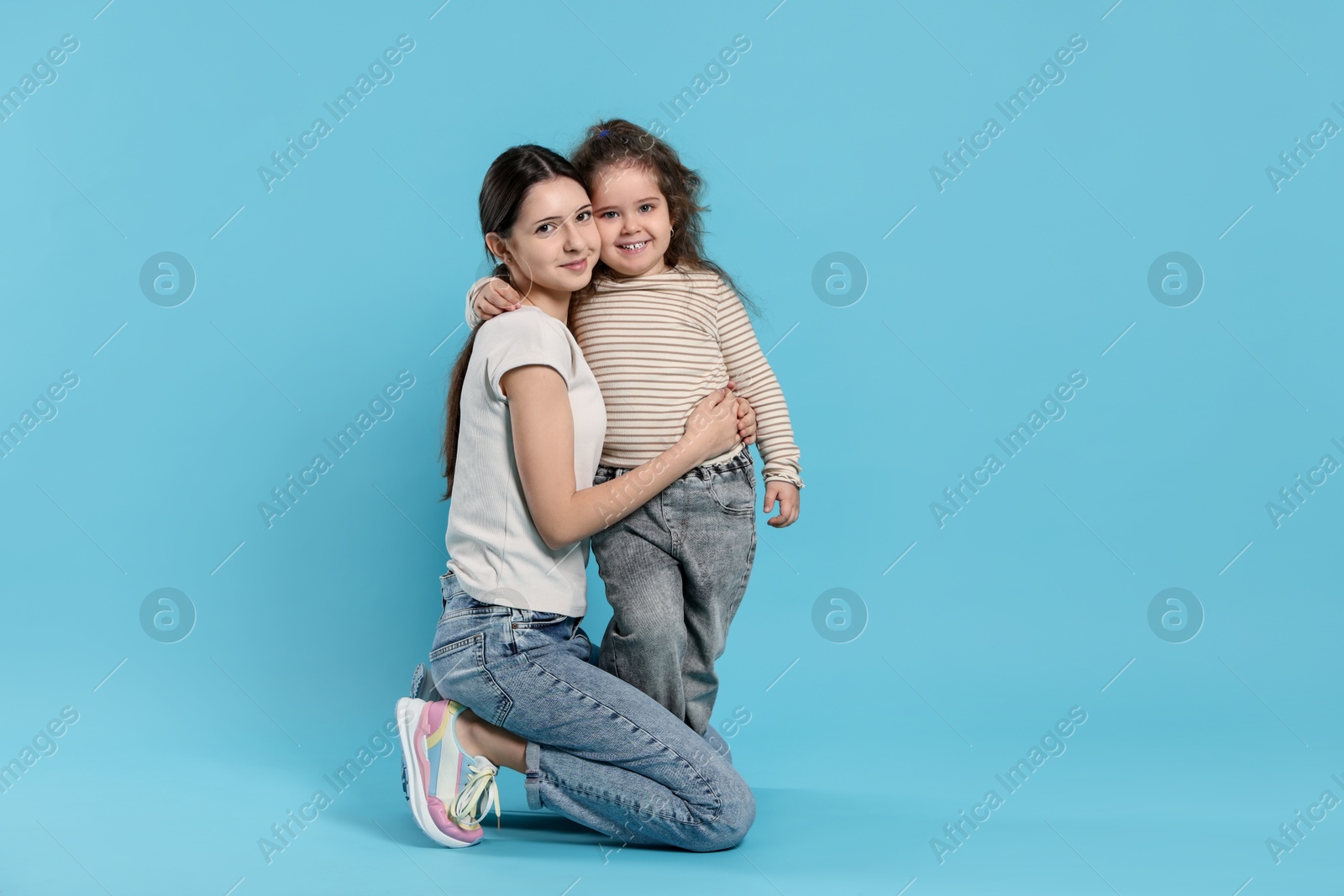 Photo of Portrait of cute sisters on light blue background