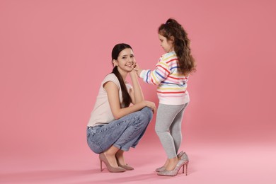 Photo of Cute little girl with lip gloss and her sister on pink background