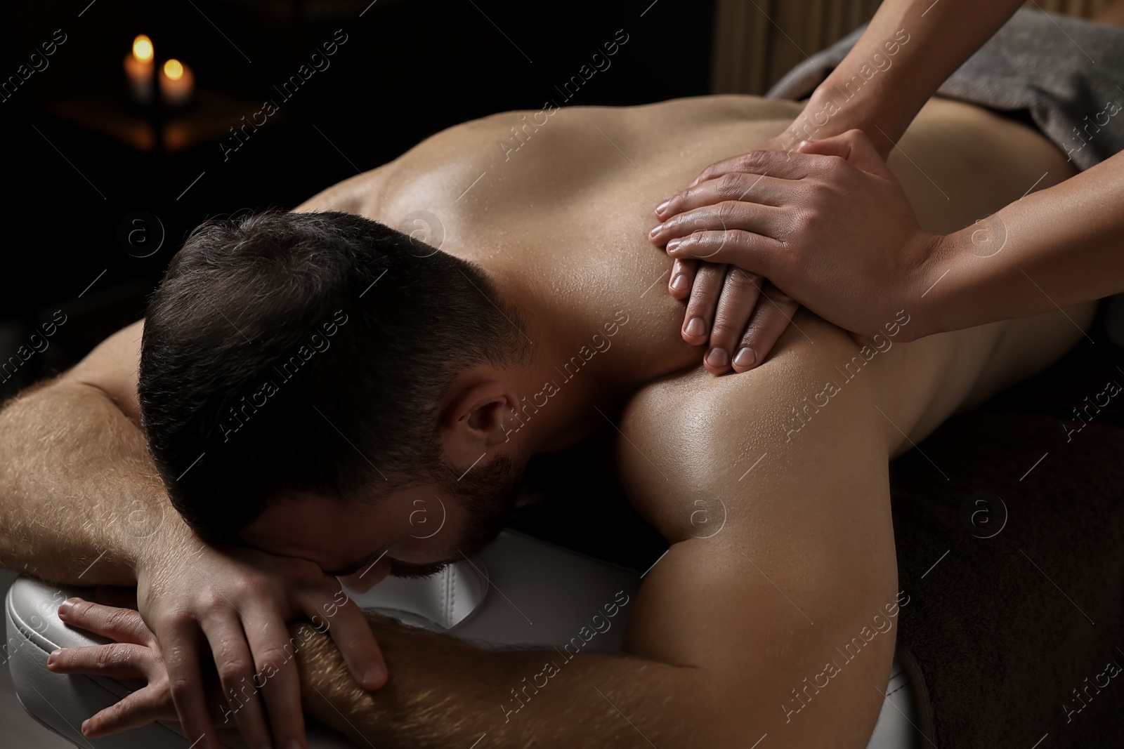 Photo of Professional physiotherapist doing shoulder massage for his client indoors, closeup