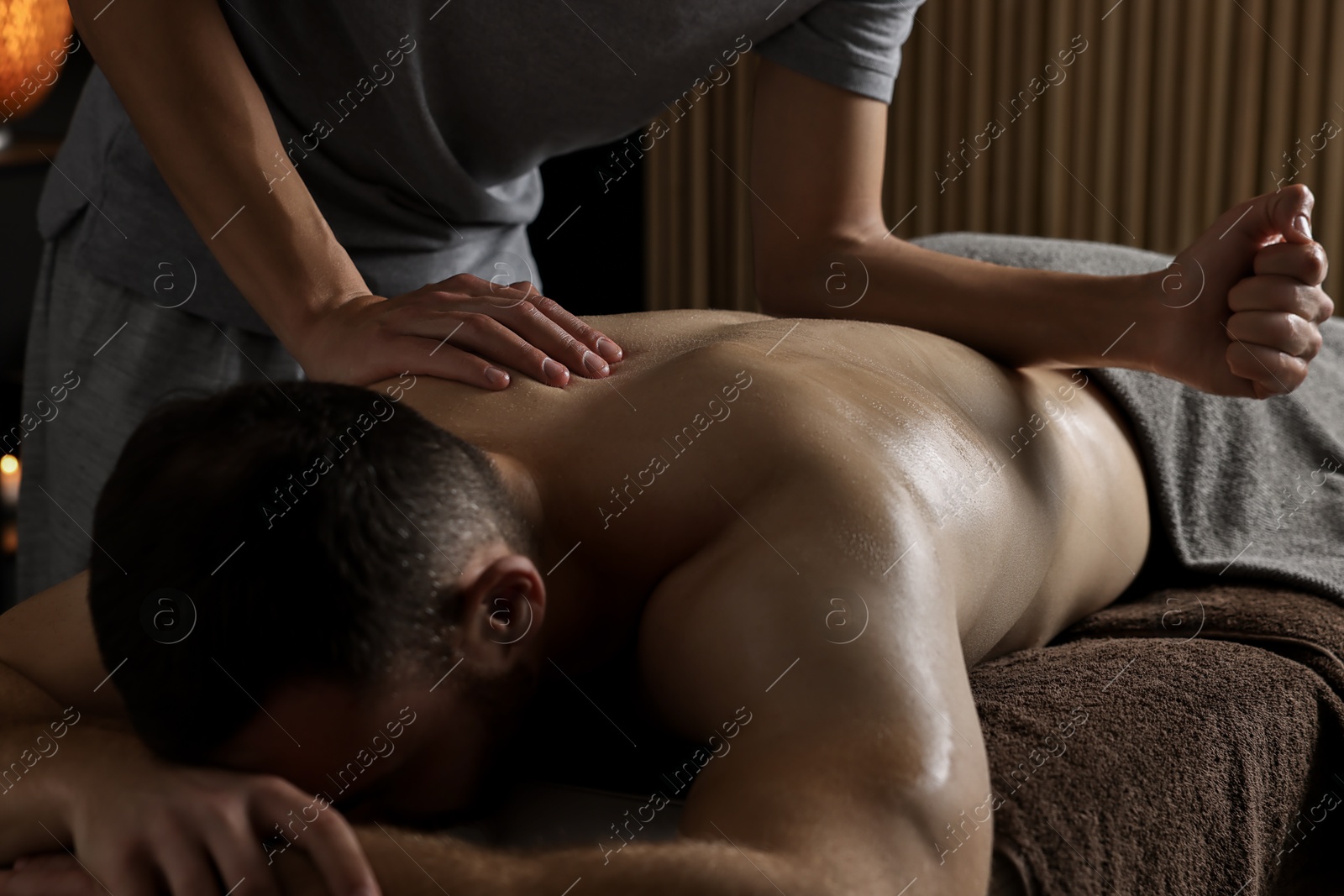 Photo of Professional physiotherapist doing back massage for his client indoors, closeup