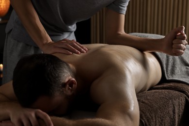 Photo of Professional physiotherapist doing back massage for his client indoors, closeup