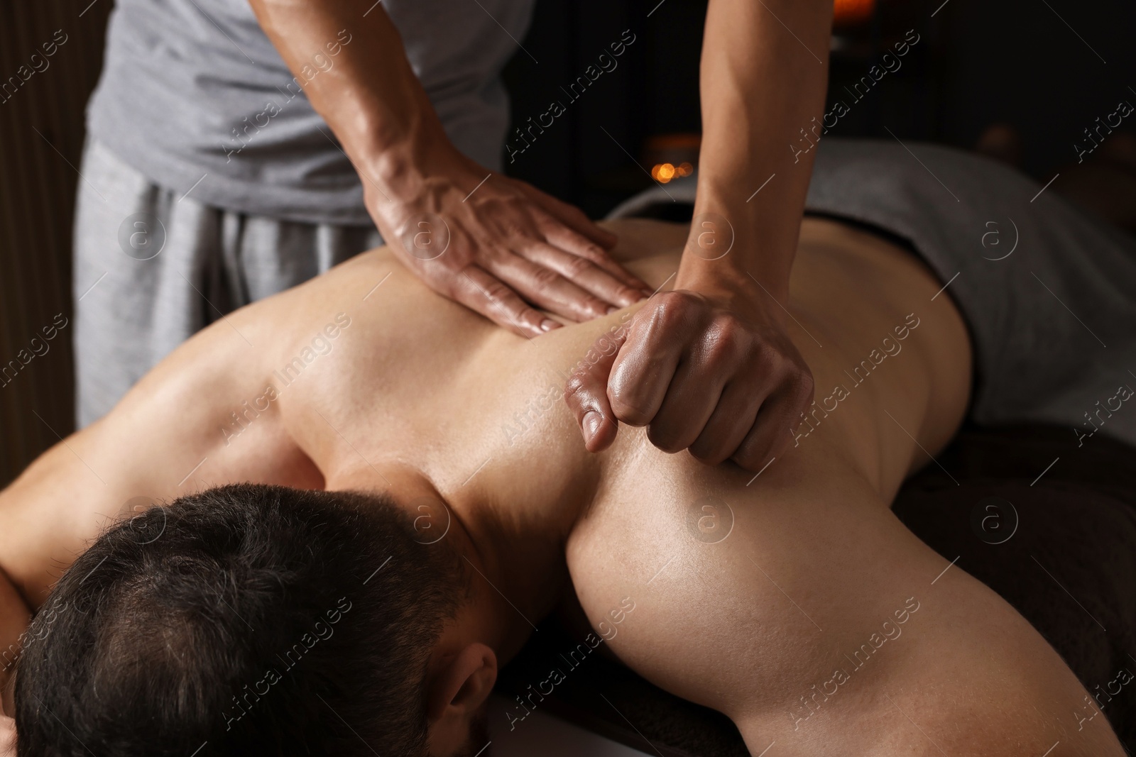 Photo of Professional physiotherapist doing shoulder massage for his client indoors, closeup