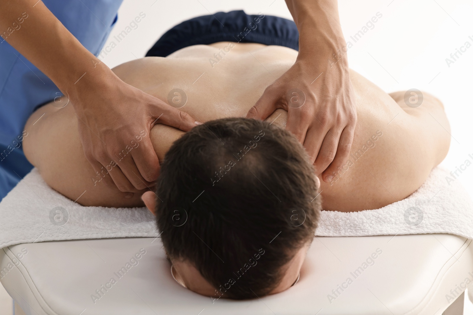 Photo of Professional physiotherapist doing neck massage for his client indoors, closeup