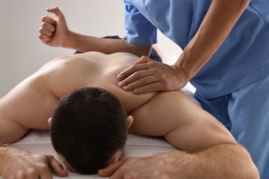 Professional physiotherapist doing back massage for his client indoors, closeup