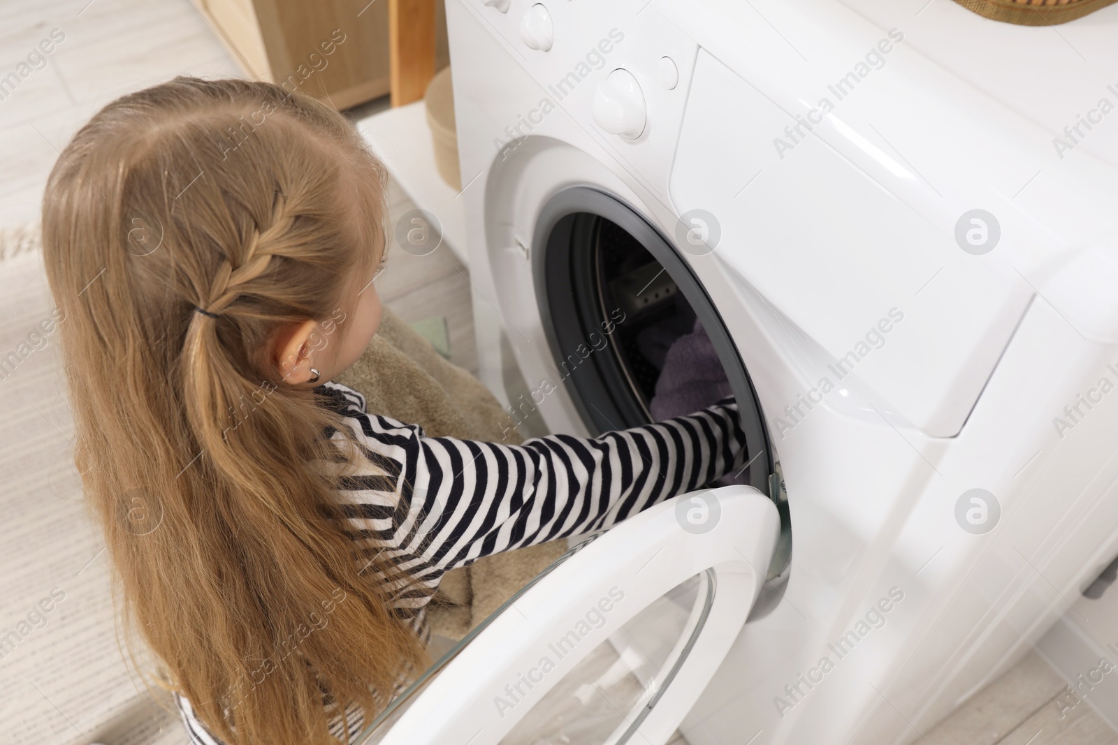 Photo of Little helper. Cute girl doing laundry at home, above view