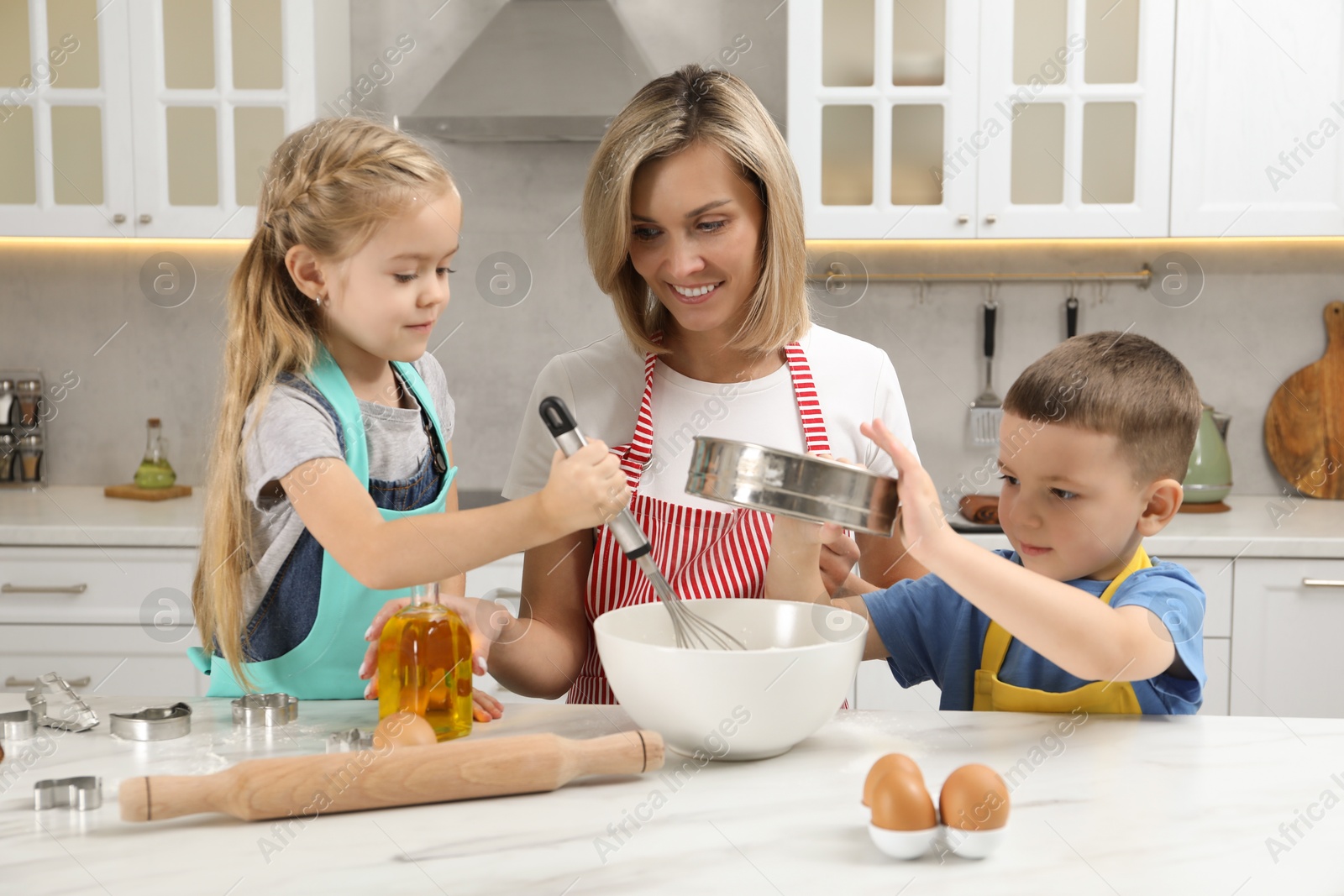 Photo of Children helping their mom making cookies in kitchen at home