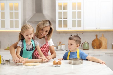 Photo of Children helping their mom making cookies in kitchen at home