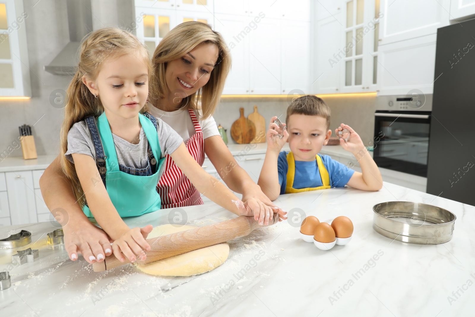 Photo of Children helping their mom making cookies in kitchen at home