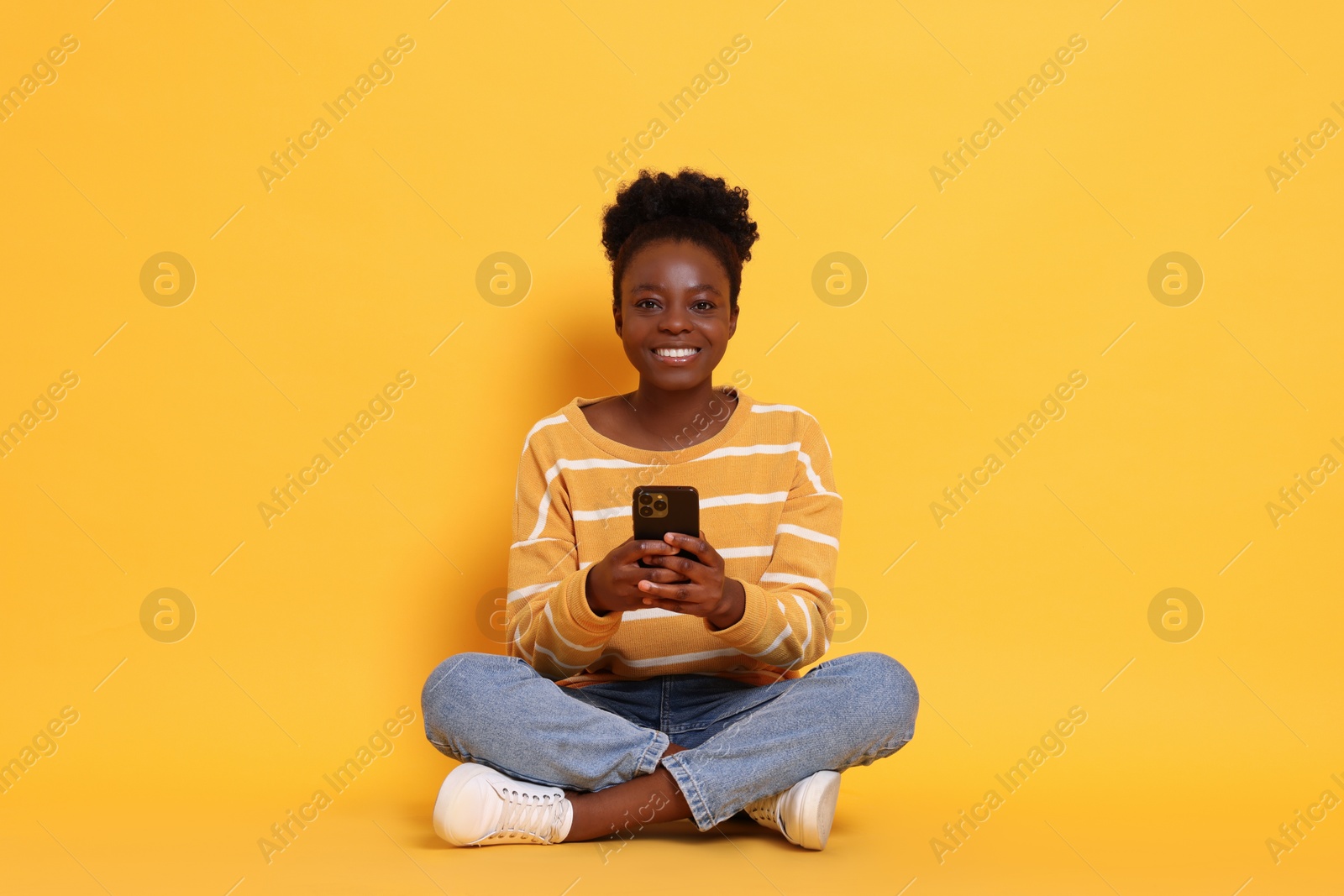 Photo of Happy woman with smartphone on yellow background