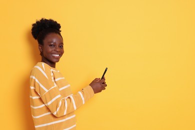 Photo of Happy woman with smartphone on yellow background. Space for text