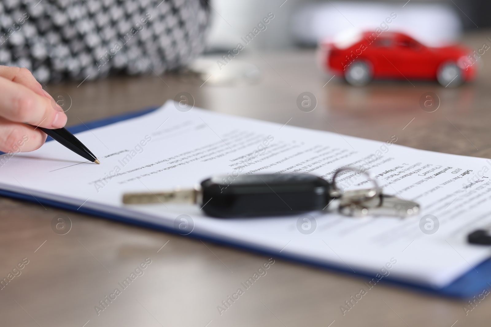 Photo of Client signing car purchase agreement at wooden table, selective focus. Buying auto