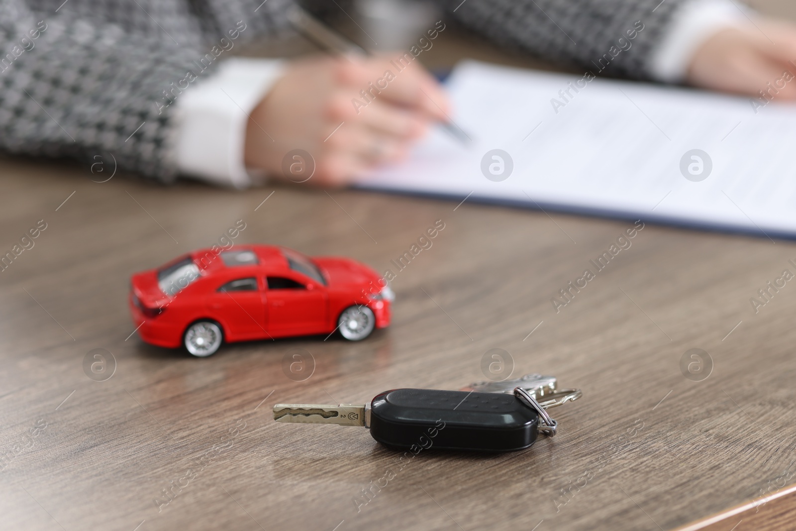 Photo of Client signing car purchase agreement at wooden table, selective focus. Buying auto