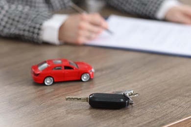 Photo of Client signing car purchase agreement at wooden table, selective focus. Buying auto