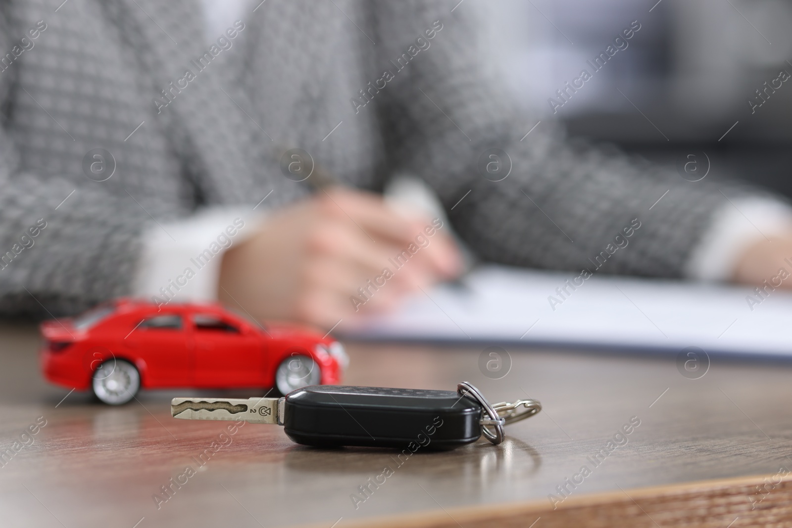 Photo of Client signing car purchase agreement at wooden table, selective focus. Buying auto