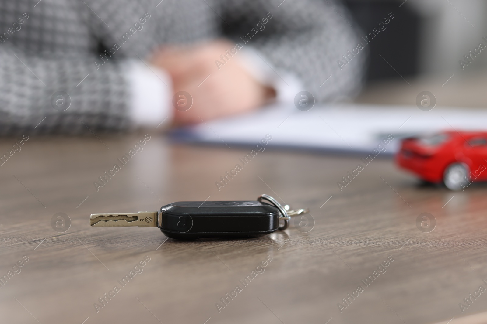 Photo of Buying auto. Car key on wooden table, selective focus